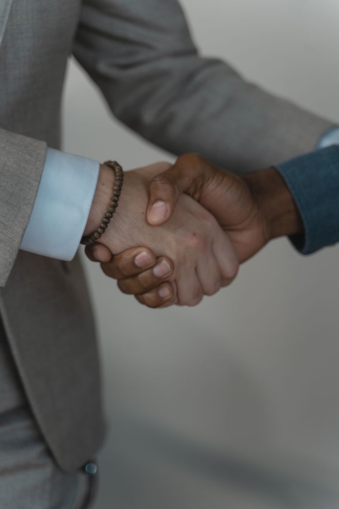 About Two business professionals shaking hands, symbolizing agreement and partnership.