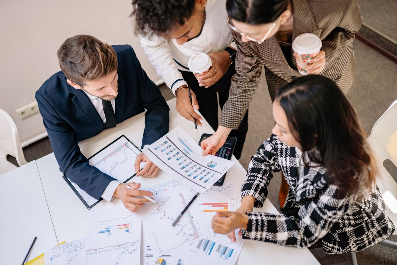 Services A diverse team in business attire collaborates over graphs and charts for a successful project.